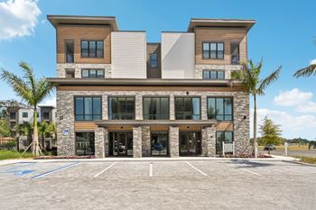 A modern two-story building with a parking lot in front.